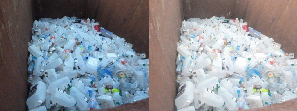 A large pile of empty plastic milk containers inside a rusted metal container.