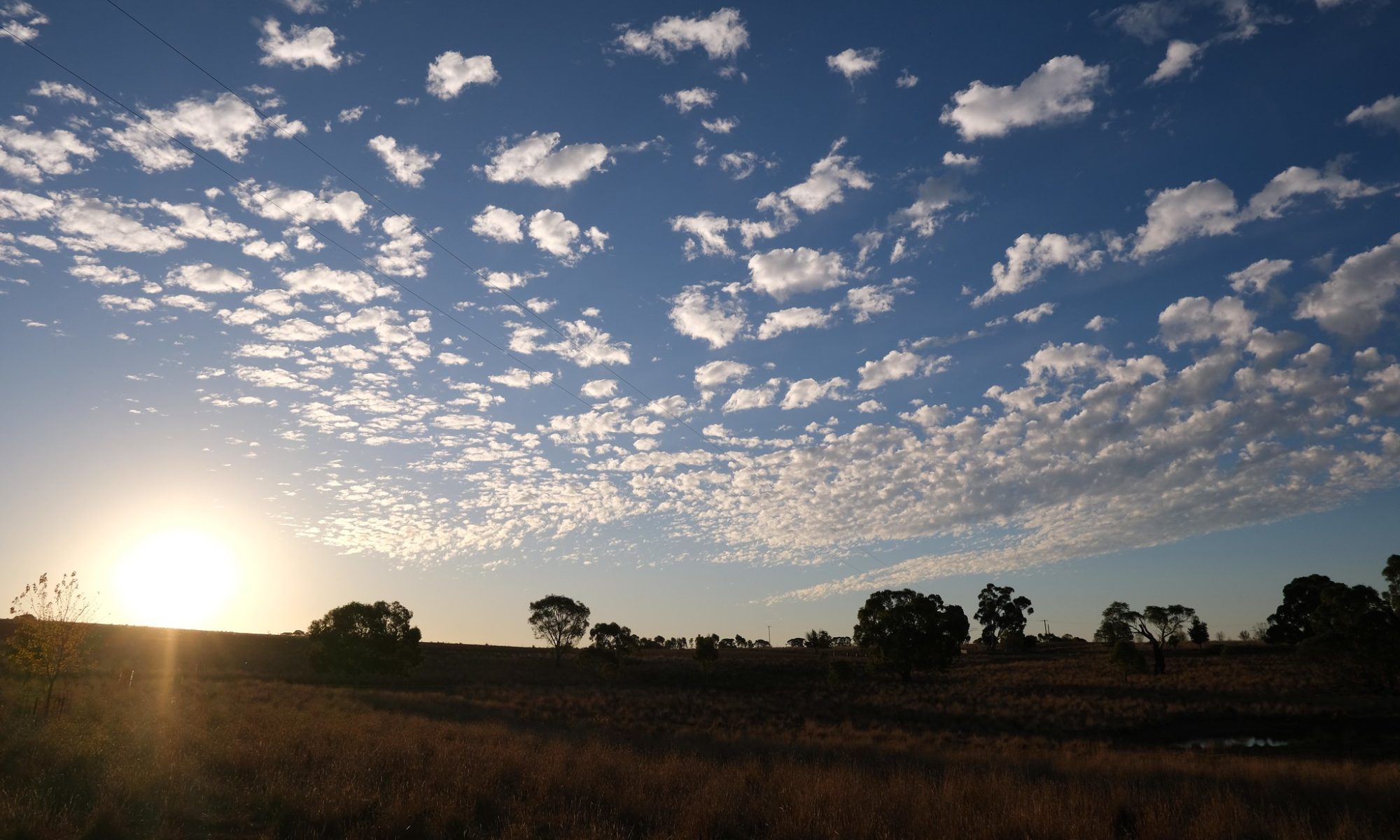 Clouds dotted above farmland at sunset